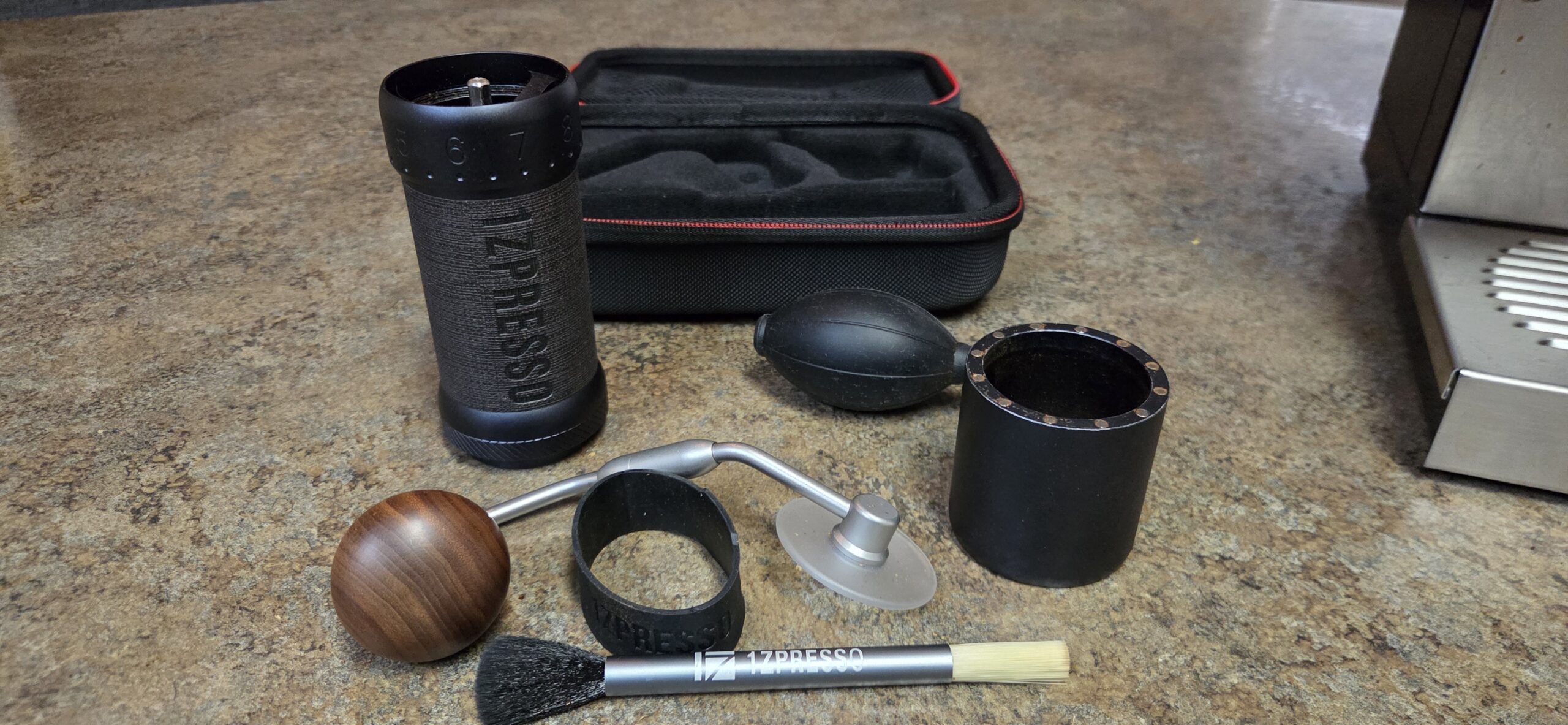 Everything included with the 1Zpresso J-Ultra: grinder, cleaning brush, air blower, silicone grip, and carrying case