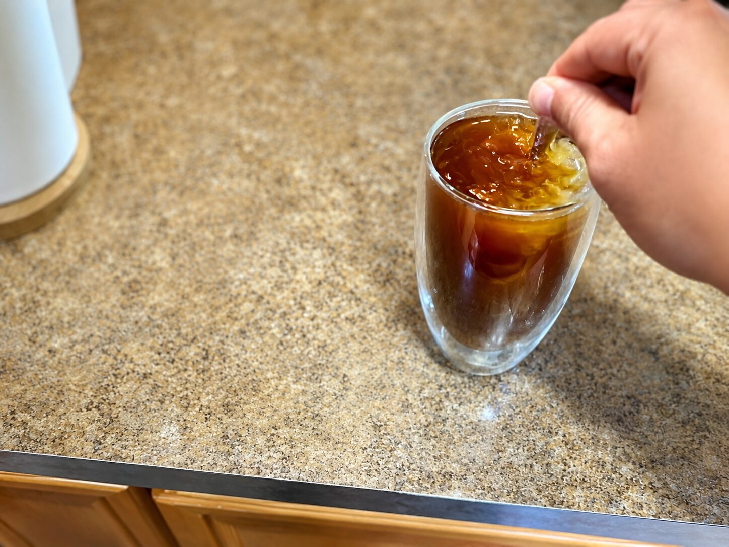 stirring a finished iced Americano before tasting