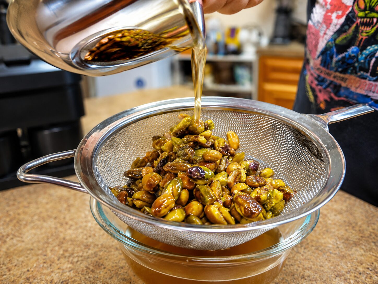 Straining pistachio syrup through a fine mesh strainer into a jar